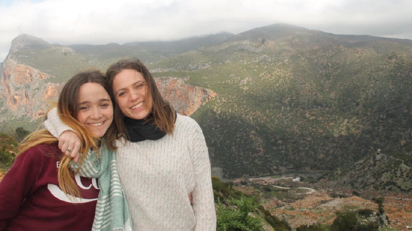 Two female students smiling and posing in Morocco, with mountains in the background, IVHQ