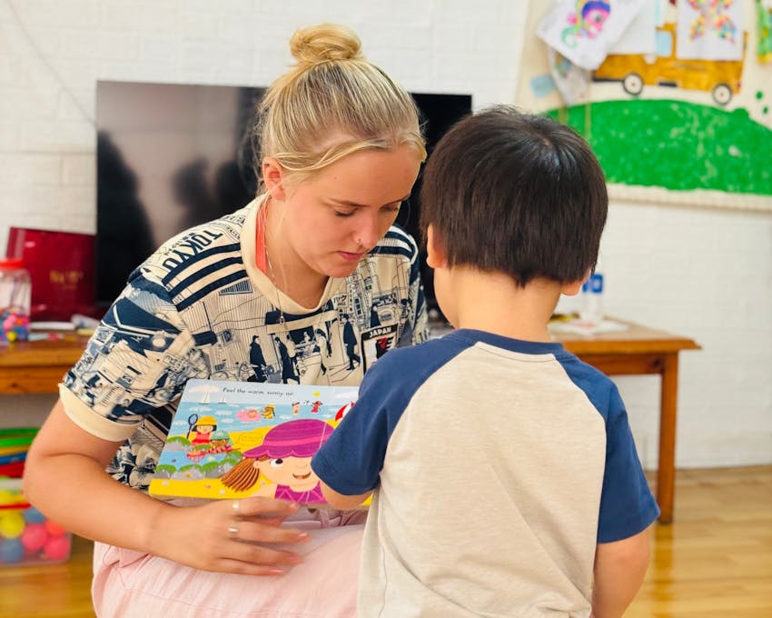 Jessica Chadwick playing an educational game with a young boy during a childcare volunteer project in Thailand
