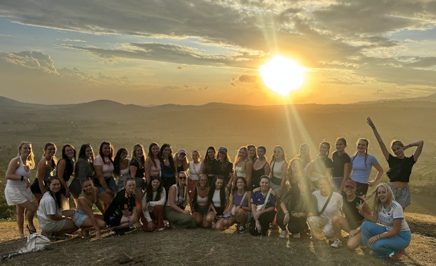 A large group of volunteers posing together during a sunset in Tanzania