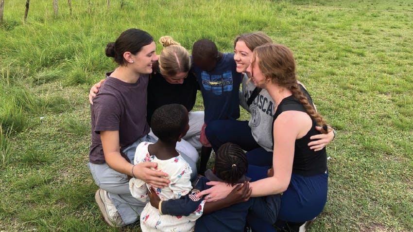 Rebekah sitting in a circle with fellow volunteers in a field in Ghana