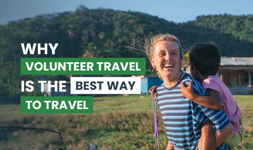 A female solo volunteer with blonde hair stands outdoors with a child surrounded by greenery and a text overlay stating ‘Why volunteer travel is the best way to travel‘