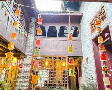 An open-air courtyard strung with handmade colorful lanterns and surrounded by traditional wooden and brick buildings.