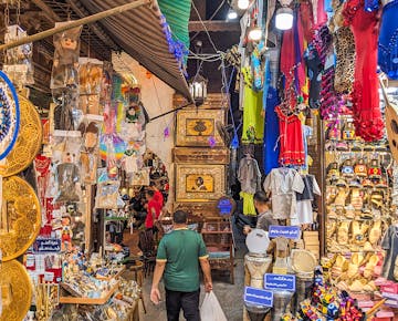 A colorful and bustling market in Cairo filled with traditional Egyptian clothing, souvenirs, drums, and lanterns.