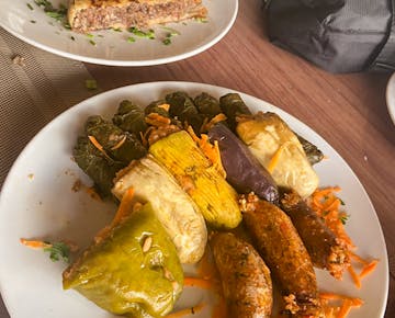 A plate of traditional mahshi including stuffed grape leaves, zucchini, peppers, cabbage, and eggplant, filled with seasoned rice.