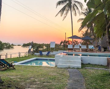 A serene view of the pool and loungers overlooking the estuary at sunset, offering volunteers a peaceful retreat at the Mozambique accommodation.