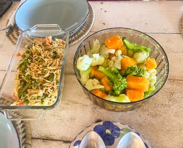 A glass bowl of mixed steamed vegetables and a dish of veggie noodles are served for lunch at the IVHQ volunteer base in Mozambique.