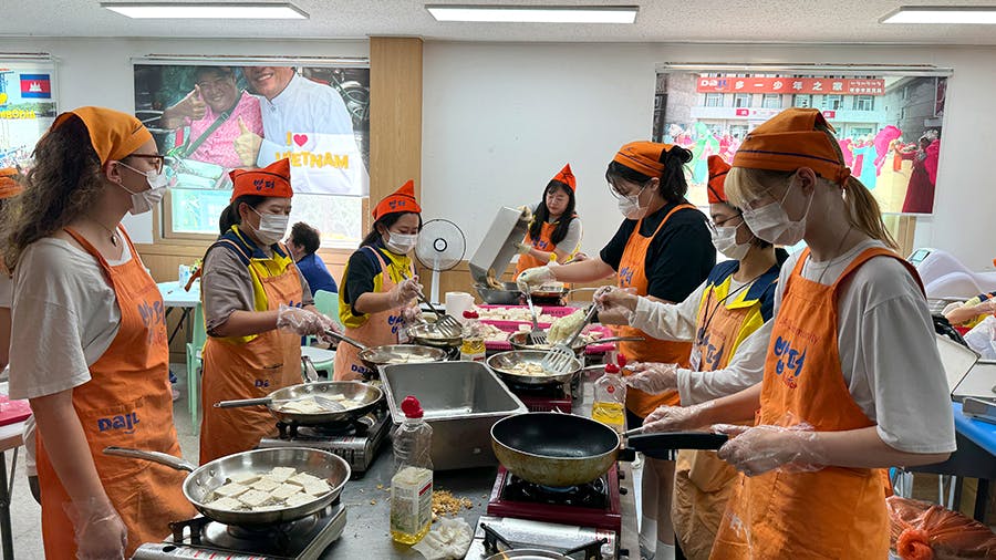 IVHQ volunteers frying tofu at the Soup Kitchen volunteer project in South Korea with IVHQ
