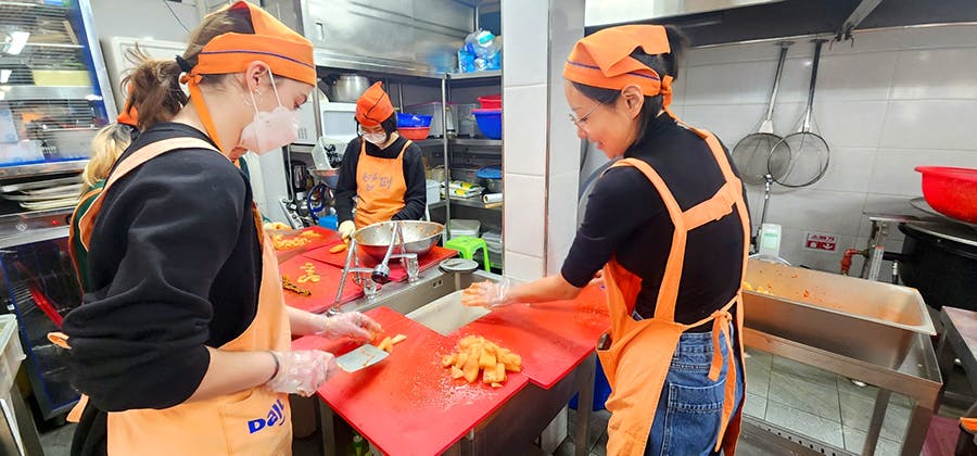 IVHQ volunteers cutting carrots at the IVHQ Soup Kitchen volunteer project in South Korea