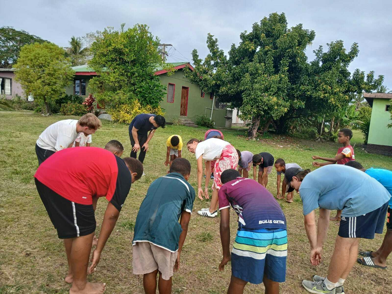 A group of IVHQ volunteers and kids stretching before starting sports activities