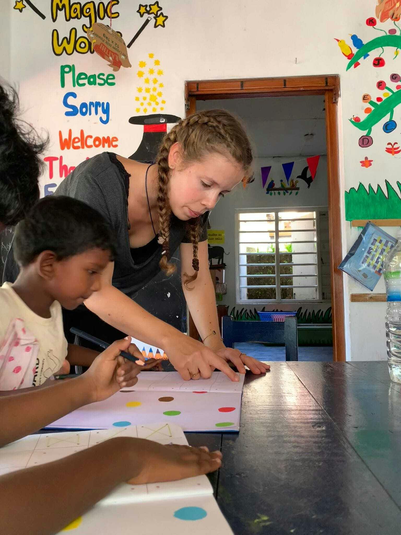 An IVHQ volunteer helping a local student with a reading exercise