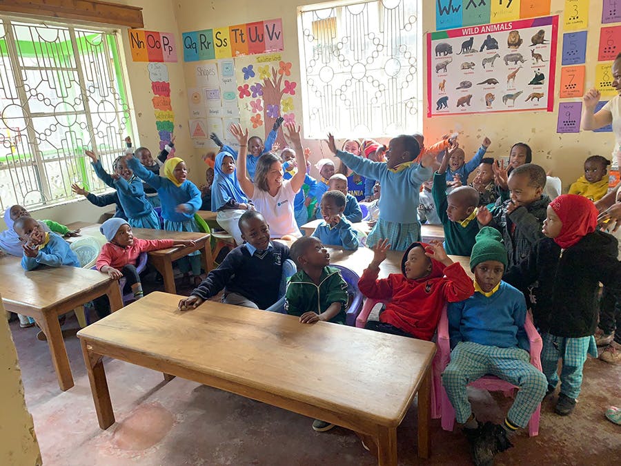 A group of happy children with IVHQ childcare volunteer in Tanzania