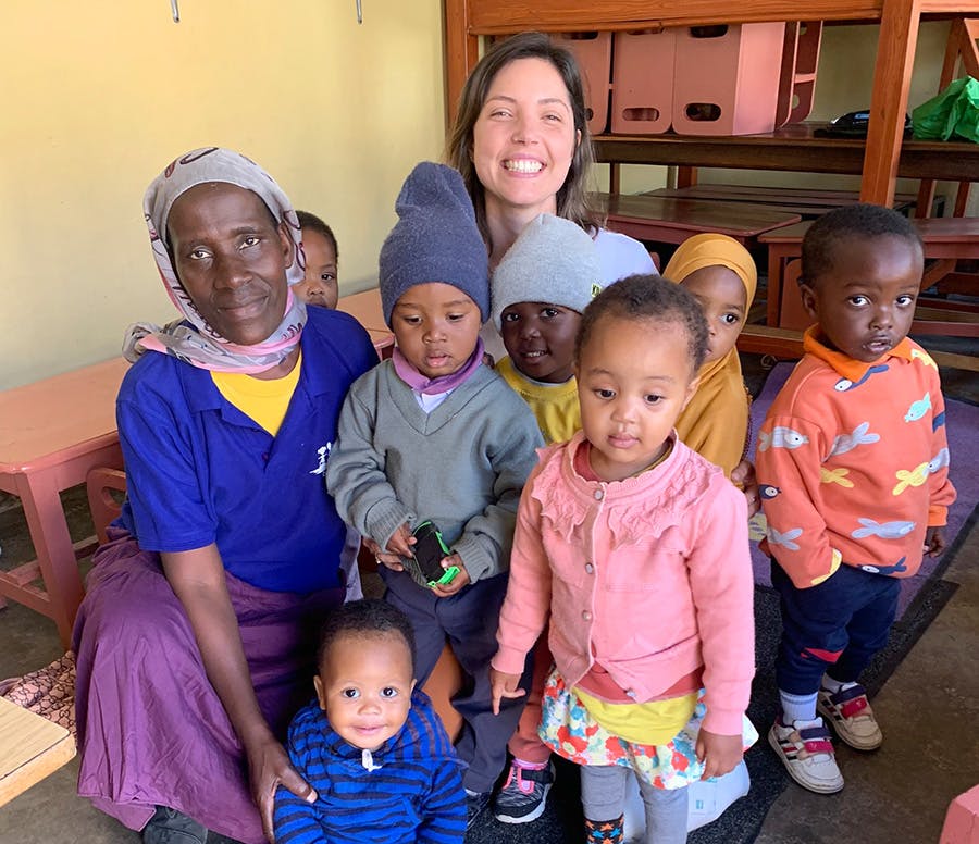 An IVHQ volunteer at the childcare project taking photo with children and local staff in Tanzania