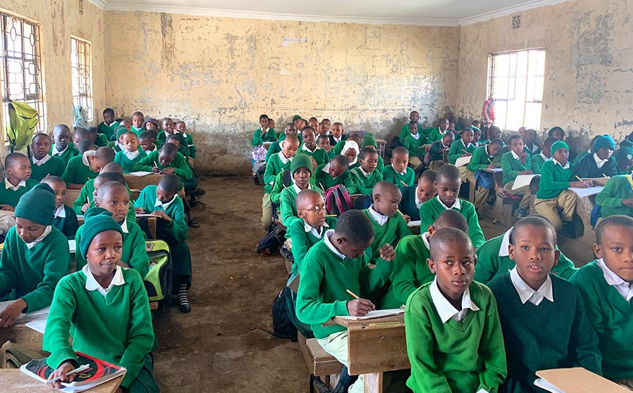 One hundred Tanzanian students in class studying with IVHQ volunteer at IVHQ Tanzania teaching project
