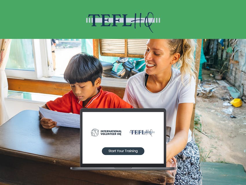 A woman teaches a child at a wooden desk using the skills learned from her TEFL course.