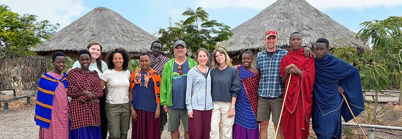 Photograph of a diversity gender, age and ethnicity group of IVHQ volunteers in Tanzania with local people wearing shuka