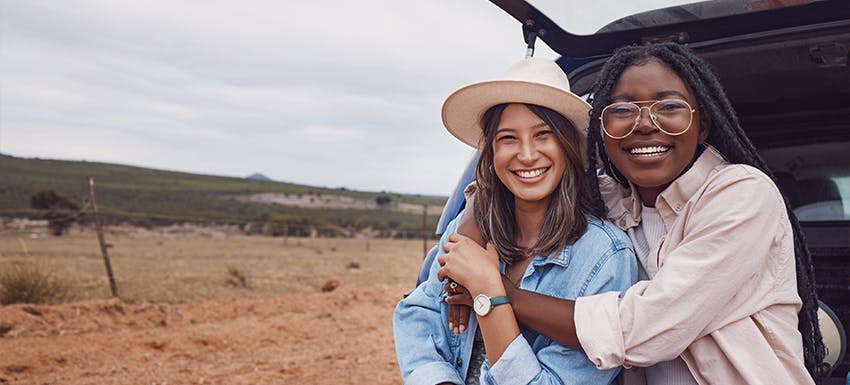 Two female volunteers hug while sitting in the boot of a car while on an outdoor adventure in Botswana with International Volunteer HQ.