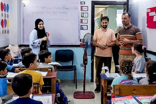 Volunteers and local teachers engage a classroom of young students during an English lesson as part of IVHQ’s Teaching English project in Cairo, Egypt, with vocabulary written on the whiteboard behind them.